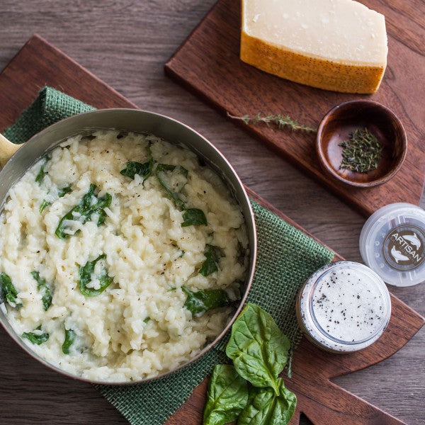 Spinach risotto next to parmesan cheese black and black truffle salt